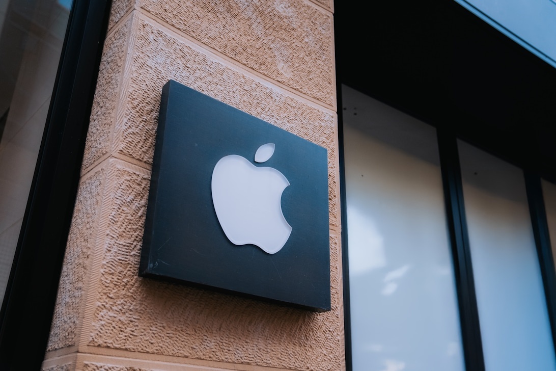 Apples vita logotyp på en mörk skylt på en texturerad byggnadsfasad, vilket representerar en av världens mest igenkännbara företagsidentiteter.