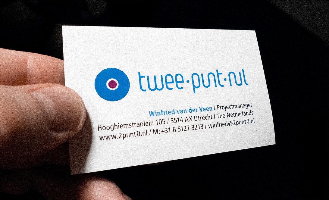 En hand som håller ett stilrent visitkort med en modern logotyp och tydlig kontaktinformation på vit kartong.
